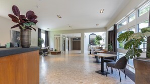 A spacious, modern lobby with a marble floor, wooden reception desk, and large windows offering natural light. - Fletcher Hotel - Restaurant Erica (Berg en Dal)