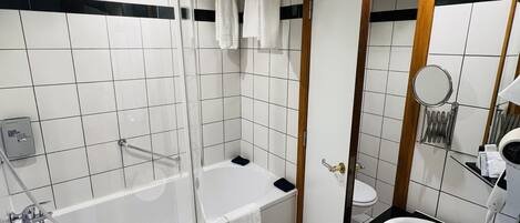 A modern bathroom with a glass-enclosed shower, a bathtub, a vanity with a sink, and a mirror.
