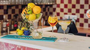Angolo bar con parete a scacchi, una ciotola di frutta e due bevande sul bancone.