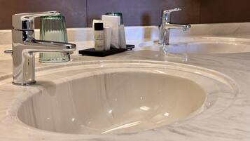 A bathroom with two sinks, each with a modern faucet, and a small tray with toiletries.