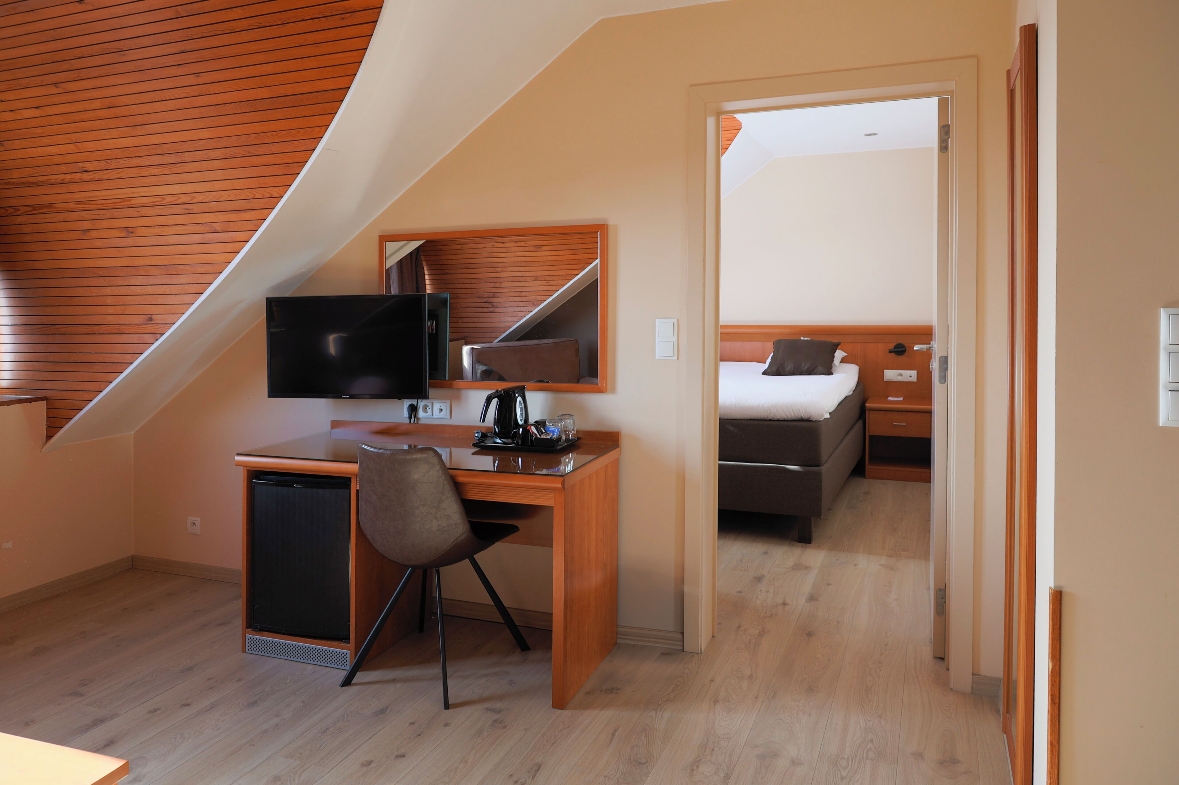Une pièce de taille modeste, comprenant un bureau, une chaise et un lit.
