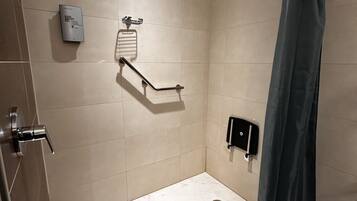 A modern shower with a handheld showerhead, a handheld shower control, and a towel rack.