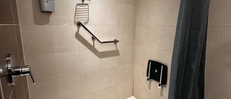 A modern shower with a handheld showerhead, a handheld shower control, and a towel rack.