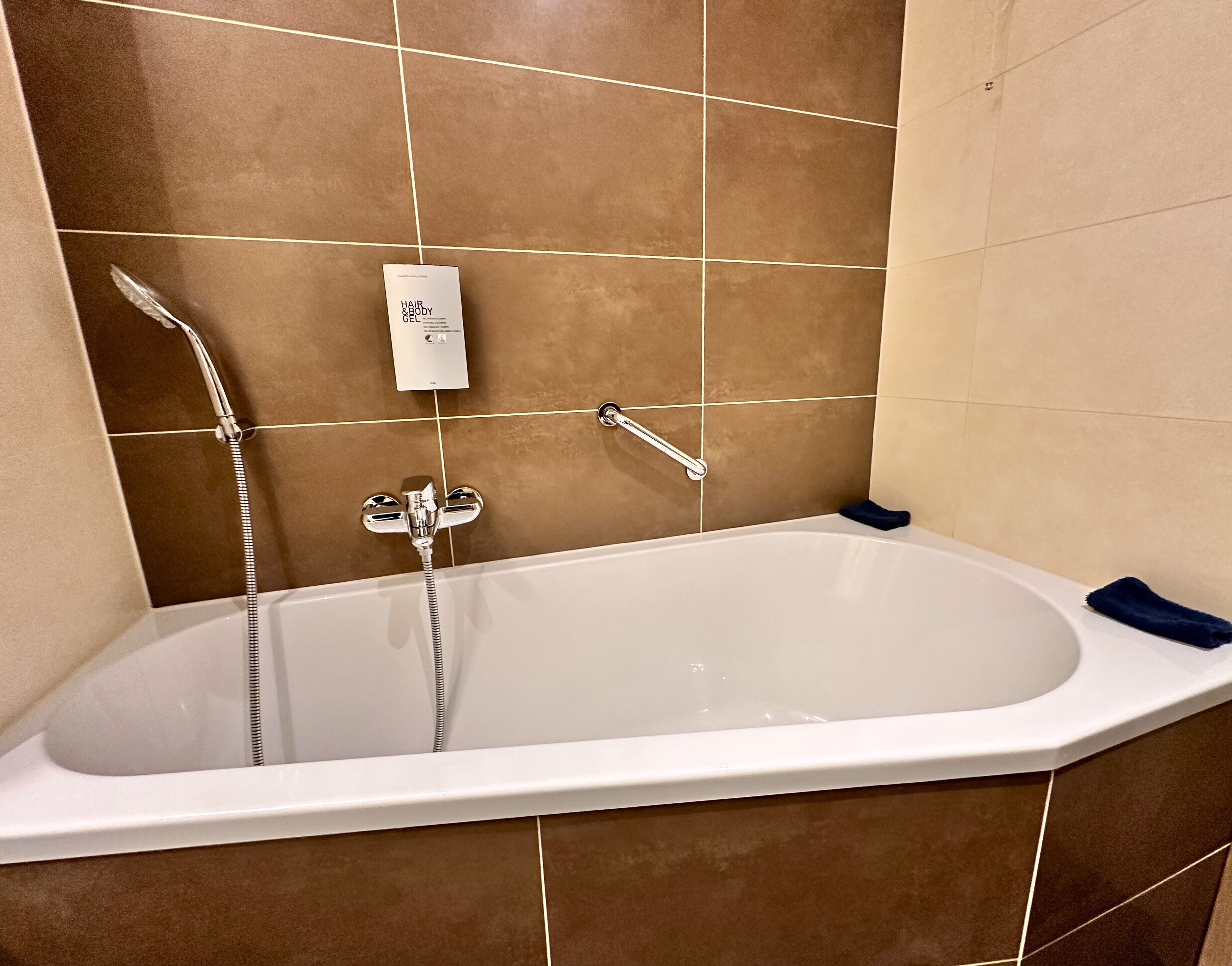 Un baño moderno con una bañera independiente, un cabezal de ducha manual y un perchero para toallas.