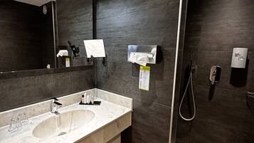 Een moderne badkamer met twee wasbakken, een spiegel, een zeepdispenser, een douche en een toilet.