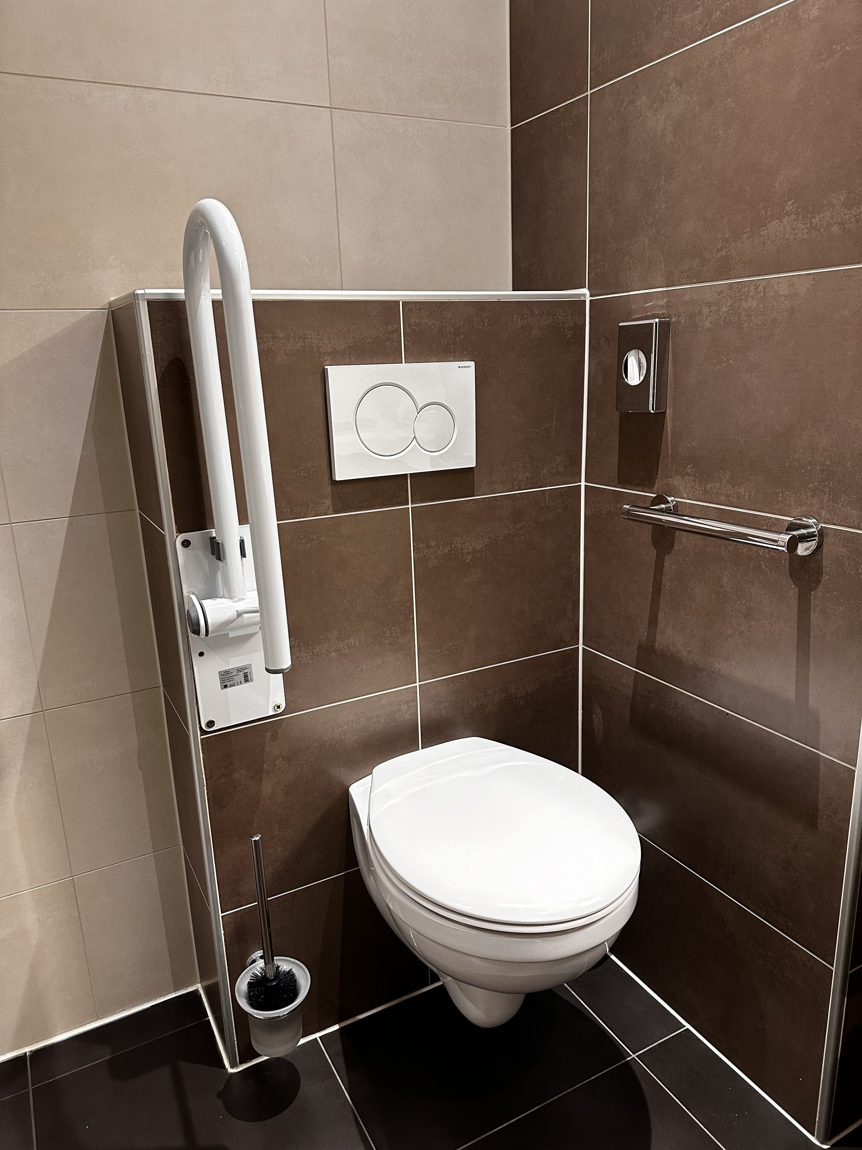 Un baño moderno con inodoro, secamanos y dispensador de jabón.