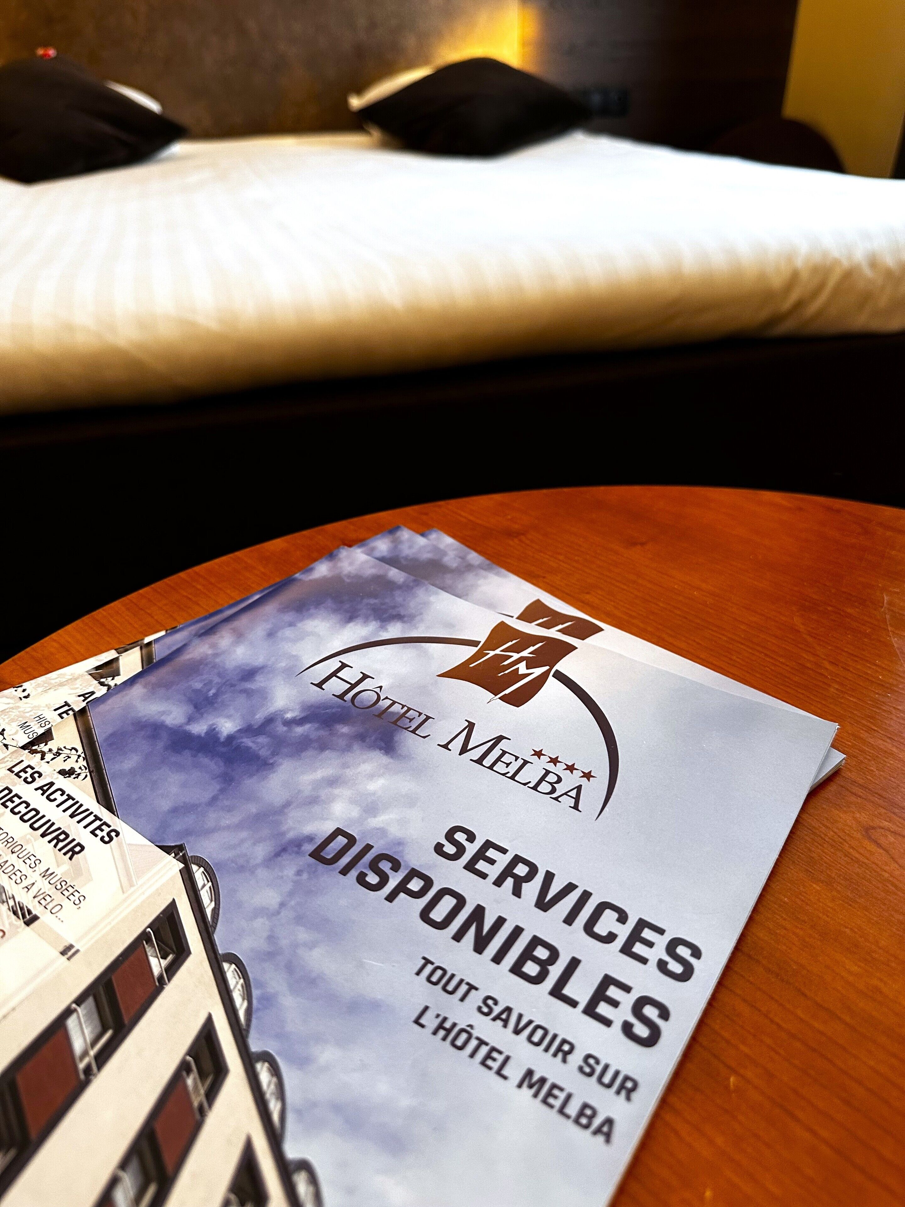A hotel brochure on a table with a view of a bed and pillows in the background.
