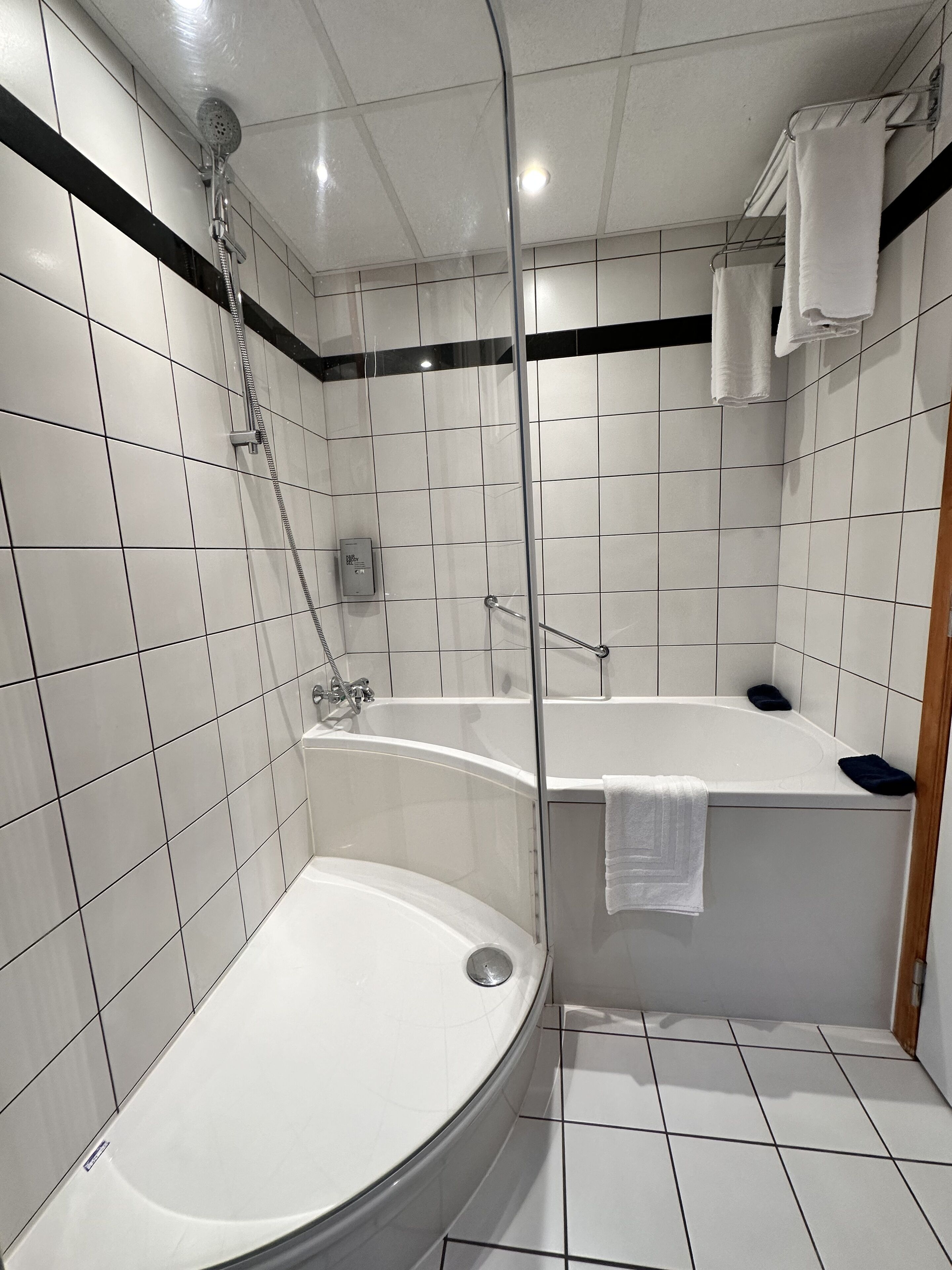 Een moderne badkamer met een bad, douche en een douchecabine met glazen wanden.