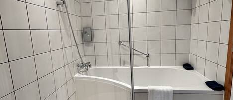 Een moderne badkamer met een bad, douche en een douchecabine met glazen wanden.