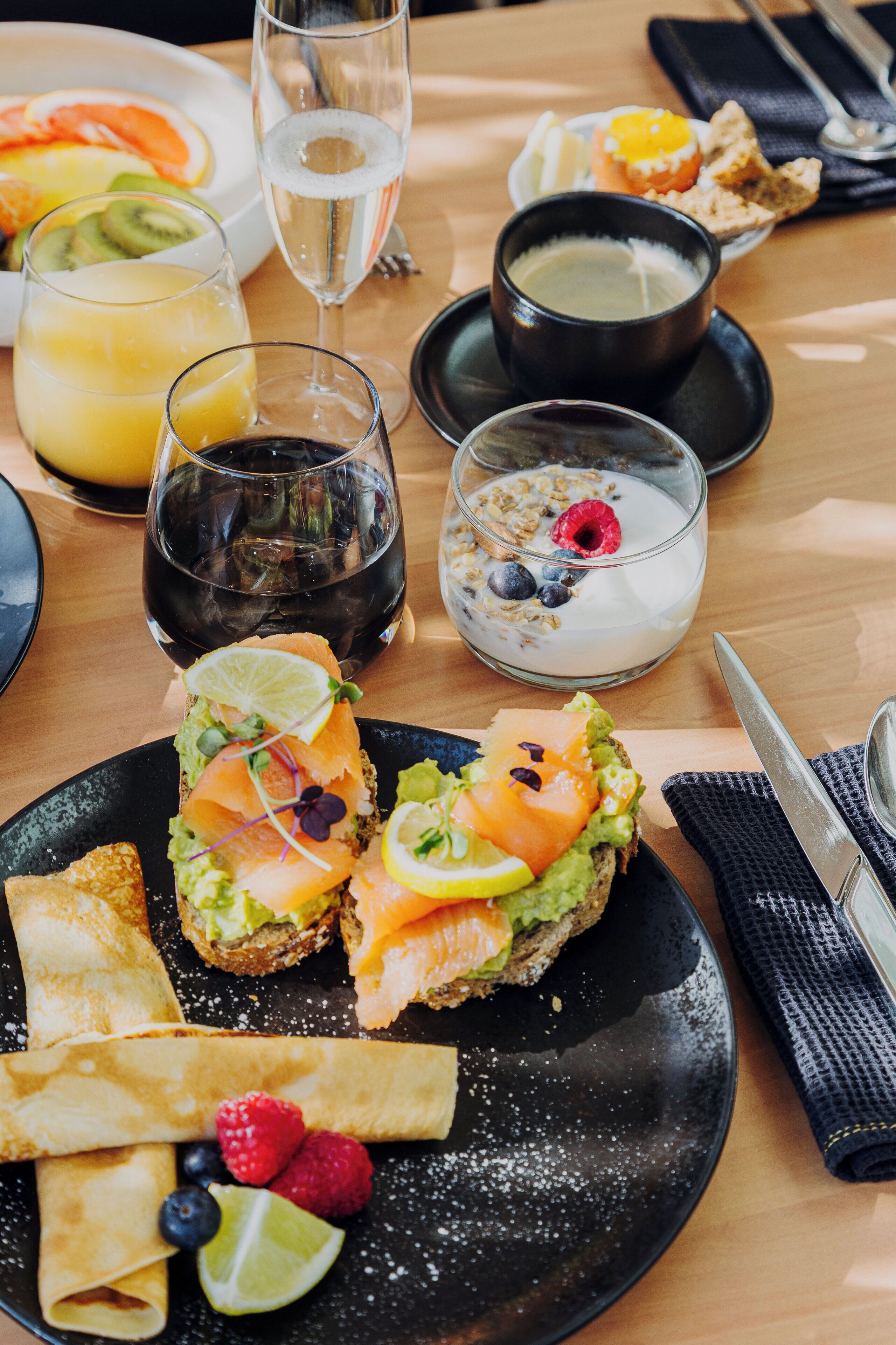 A breakfast setting with various dishes including avocado toast, a bowl of fruit, and a glass of juice.
