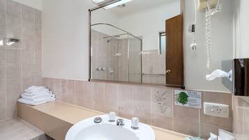Ein Hotelbad mit Waschbecken, Spiegel und einem Stapel weißer Handtücher.