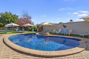 Relax by the pool surrounded by lush greenery and comfortable lounge chairs.