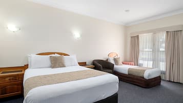 Une chambre d’hôtel avec deux lits, une table de chevet en bois, une chaise et une fenêtre avec des rideaux.