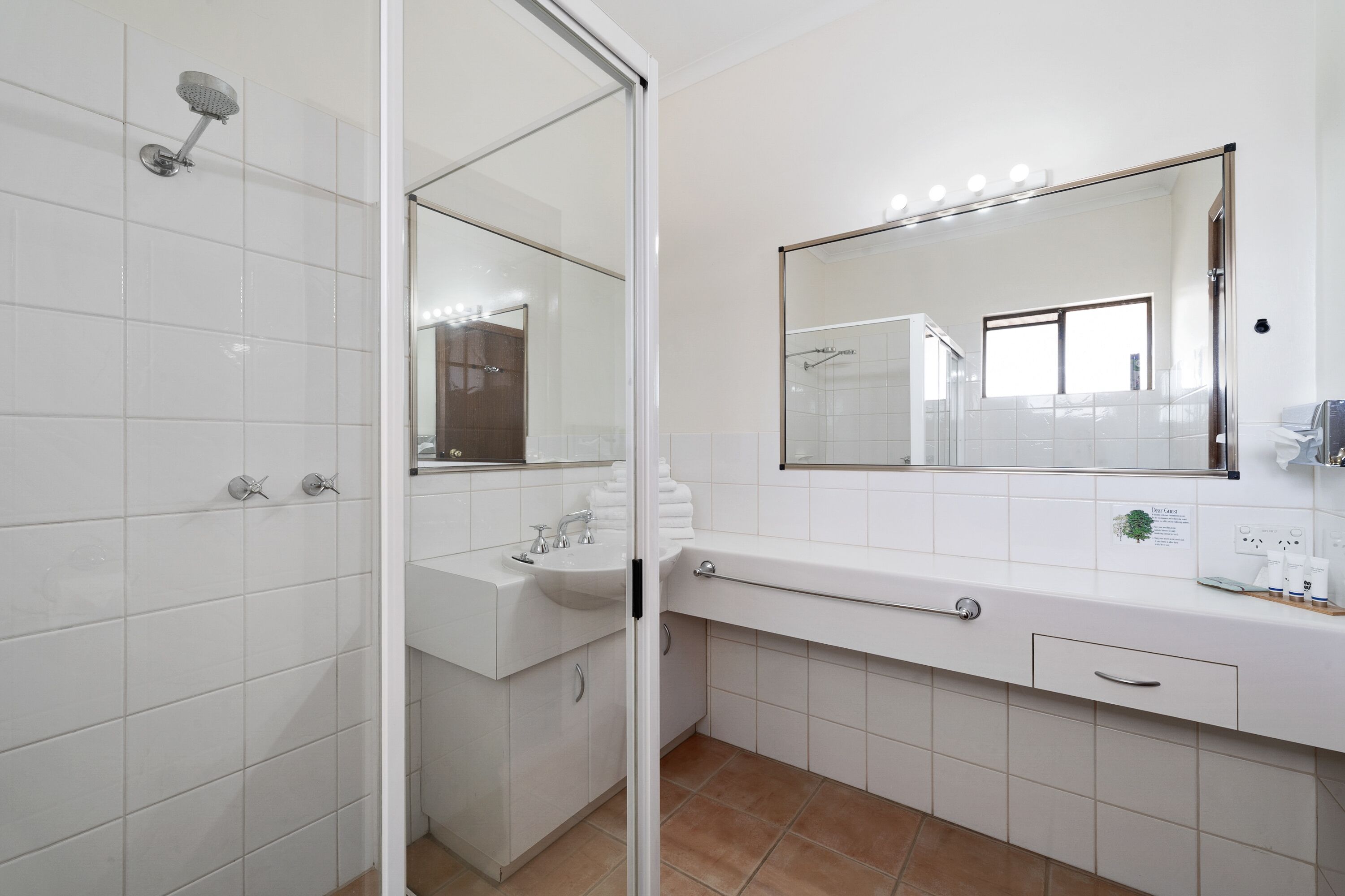 Un baño moderno con cabina de ducha de vidrio, un lavamanos blanco y un espejo grande.
