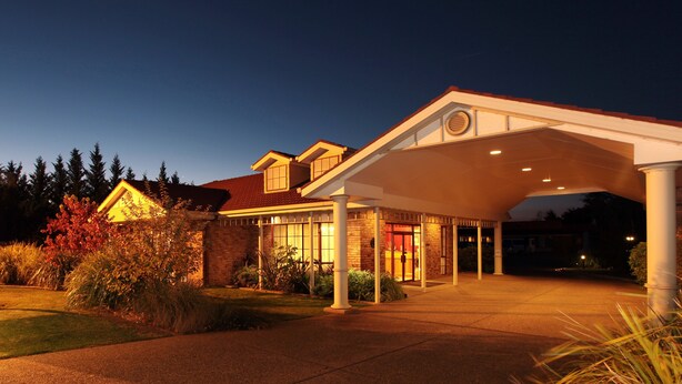 Um hotel com entrada coberta, fachada de tijolo e área de acesso bem iluminada.