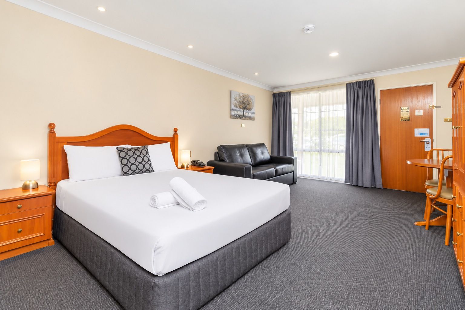A hotel room with a large bed, a desk, a chair, and a sofa.