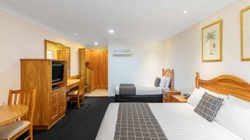 A hotel room with a bed, a desk, a television, and a wardrobe.