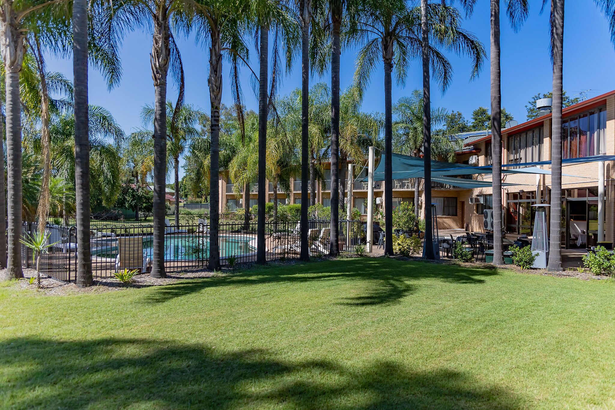 Un complexe hôtelier doté d’une piscine, de palmiers et d’un bâtiment au toit rouge.