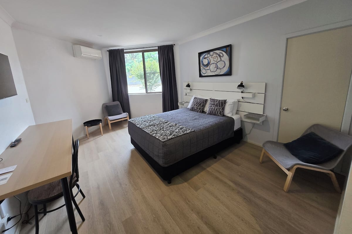 Une chambre d’hôtel moderne, dotée d’un grand lit, d’un bureau et d’une chaise.