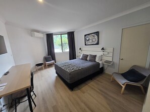 A modern hotel room with a large bed, a desk, and a chair.
