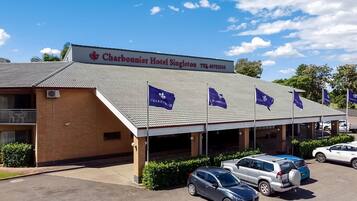 Hotel Charbonnier Singleton met pannendak, meerdere vlaggen en verschillende geparkeerde auto's.