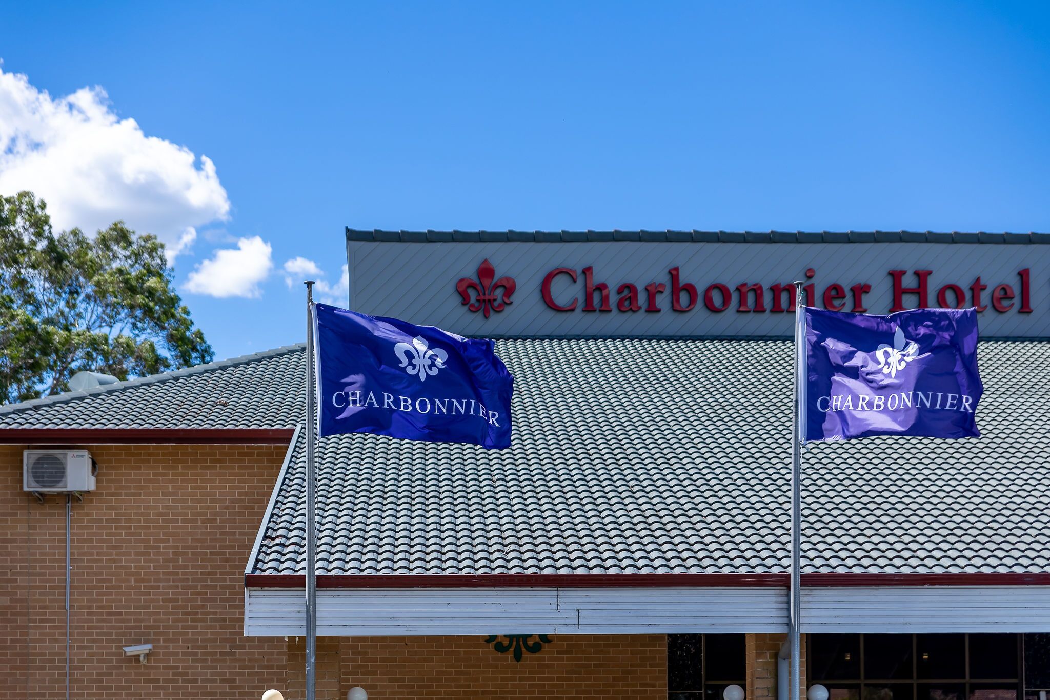 The Charbonnier Hotel with a tiled roof and two flags.