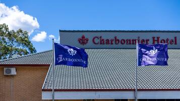 The Charbonnier Hotel with a tiled roof and two flags.
