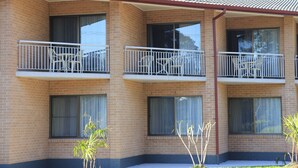 A multi-story brick building with balconies, large windows, and a tiled roof.