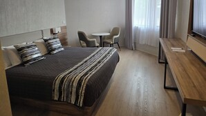 A hotel room with a large bed, a desk, a chair, and a TV. - Charbonnier Motor Inn (Singleton)