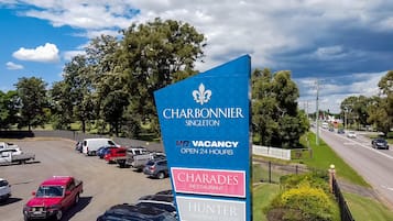 A parking lot with a sign for Charbonnier Singleton, indicating no vacancies and open 24 hours.