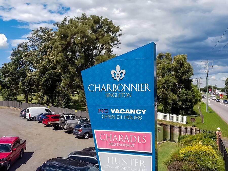 A parking lot with a sign for Charbonnier Singleton, indicating no vacancies and open 24 hours.