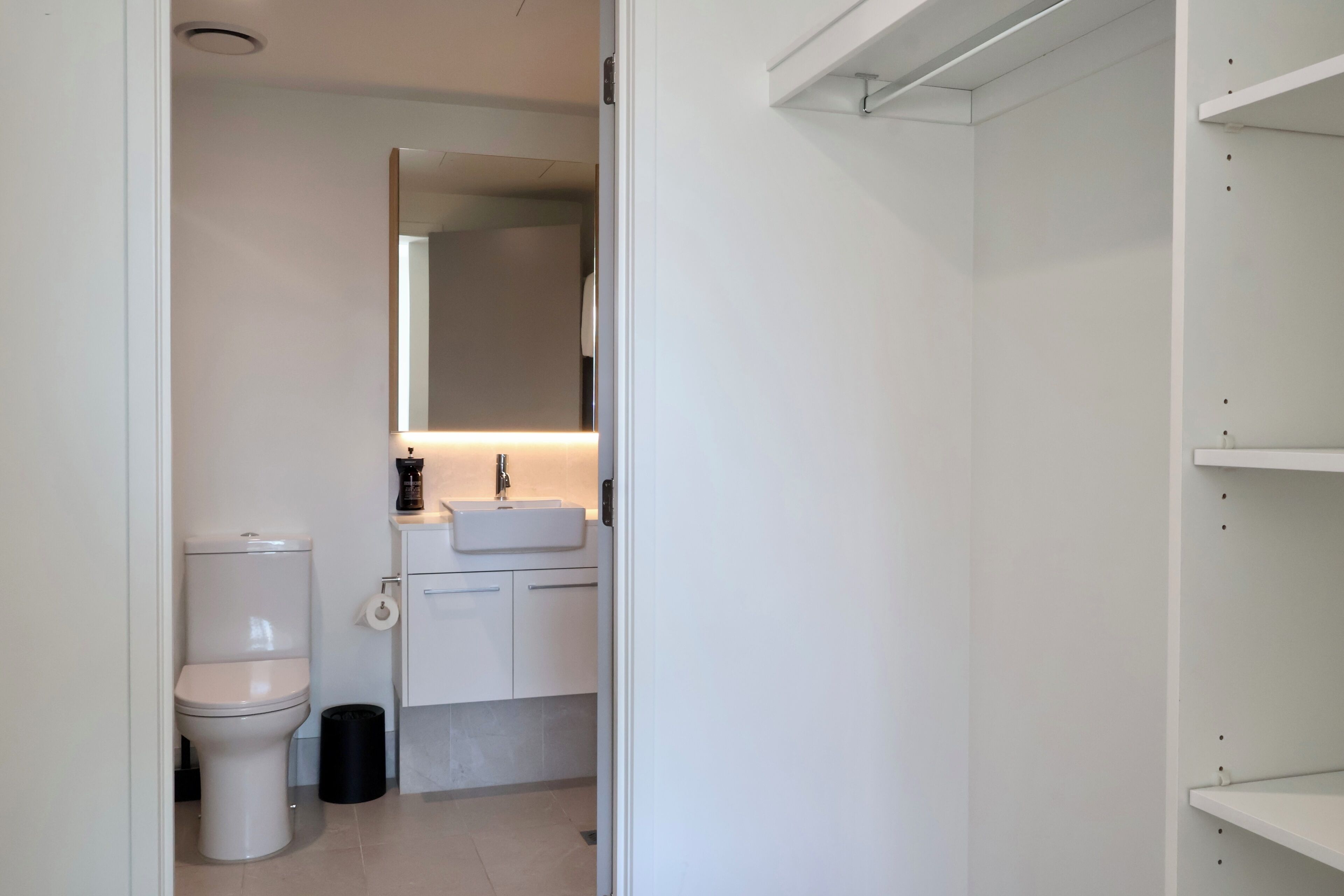 A bathroom with a toilet, sink, and mirror.