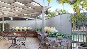 An outdoor patio area with stone flooring, metal furniture, and a covered seating area with cushions. - Brisbane International - Virginia (Boondall)