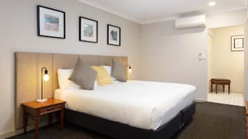 A neatly arranged hotel room with a large bed, bedside lamps, and framed pictures on the wall.