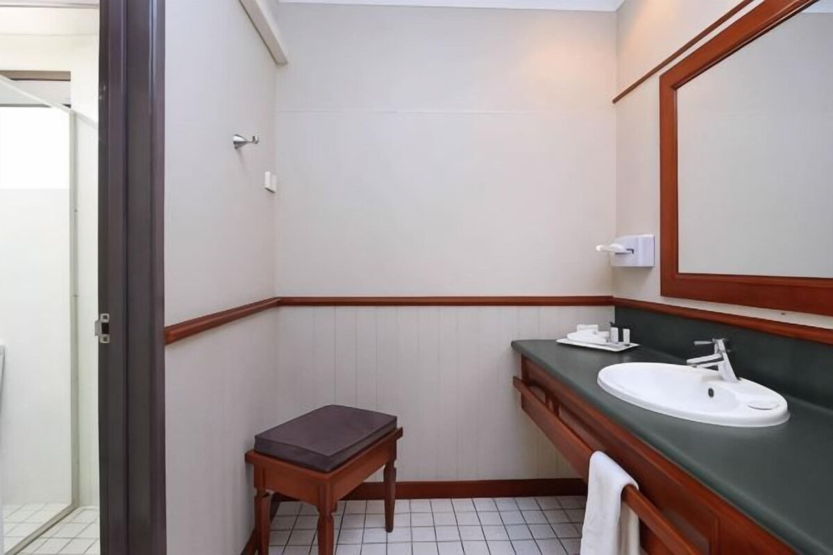 A bathroom with a sink, mirror, and a small table.