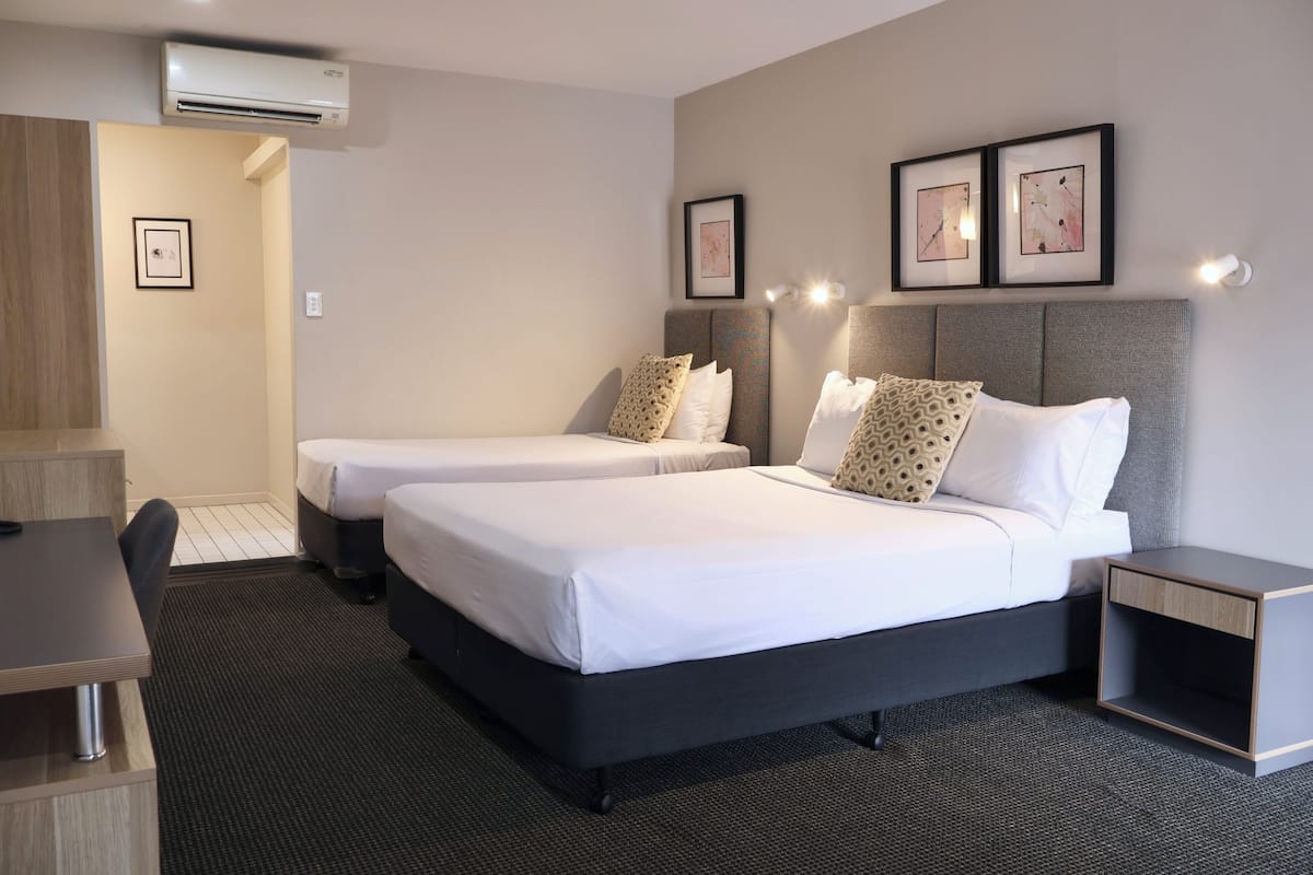 A hotel room with two beds, a desk, and a chair.