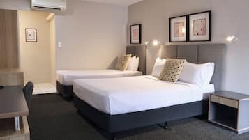 Habitación de hotel con dos camas, un escritorio y una silla.