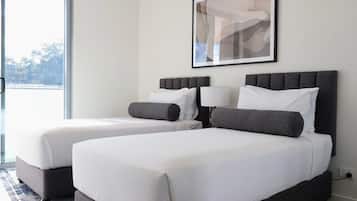 A hotel room with two beds, a large window, and a framed artwork on the wall.