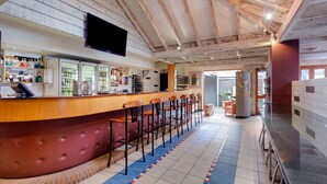 A bar area with a wooden counter, multiple stools, and a television mounted on the wall. - Brisbane International - Virginia (Boondall)
