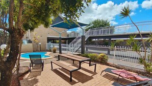 An outdoor patio with a pool, seating, and a staircase leading to an upper level. - Ambassador Motor Lodge (Hervey Bay)