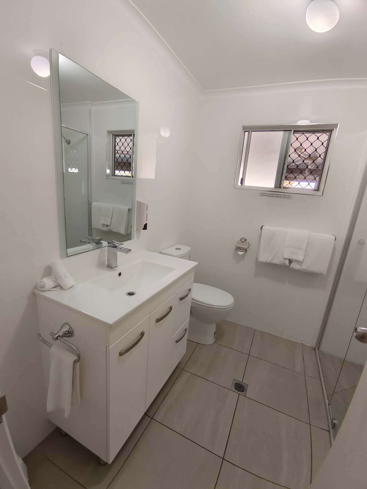 A modern bathroom with a white vanity, a toilet, and a shower area.