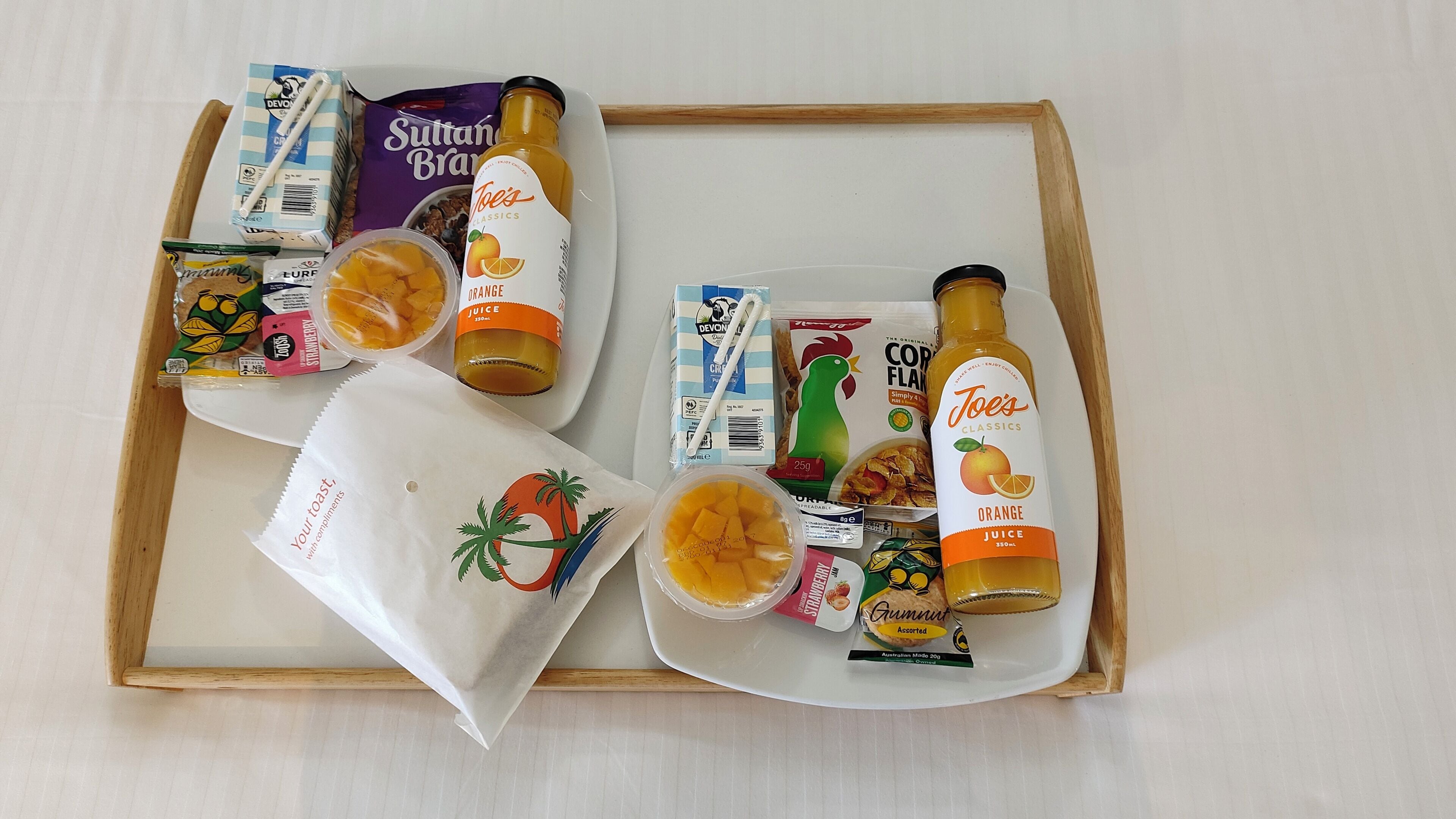 A tray with various food items and drinks, including orange juice, cereal, and a bag of snacks.