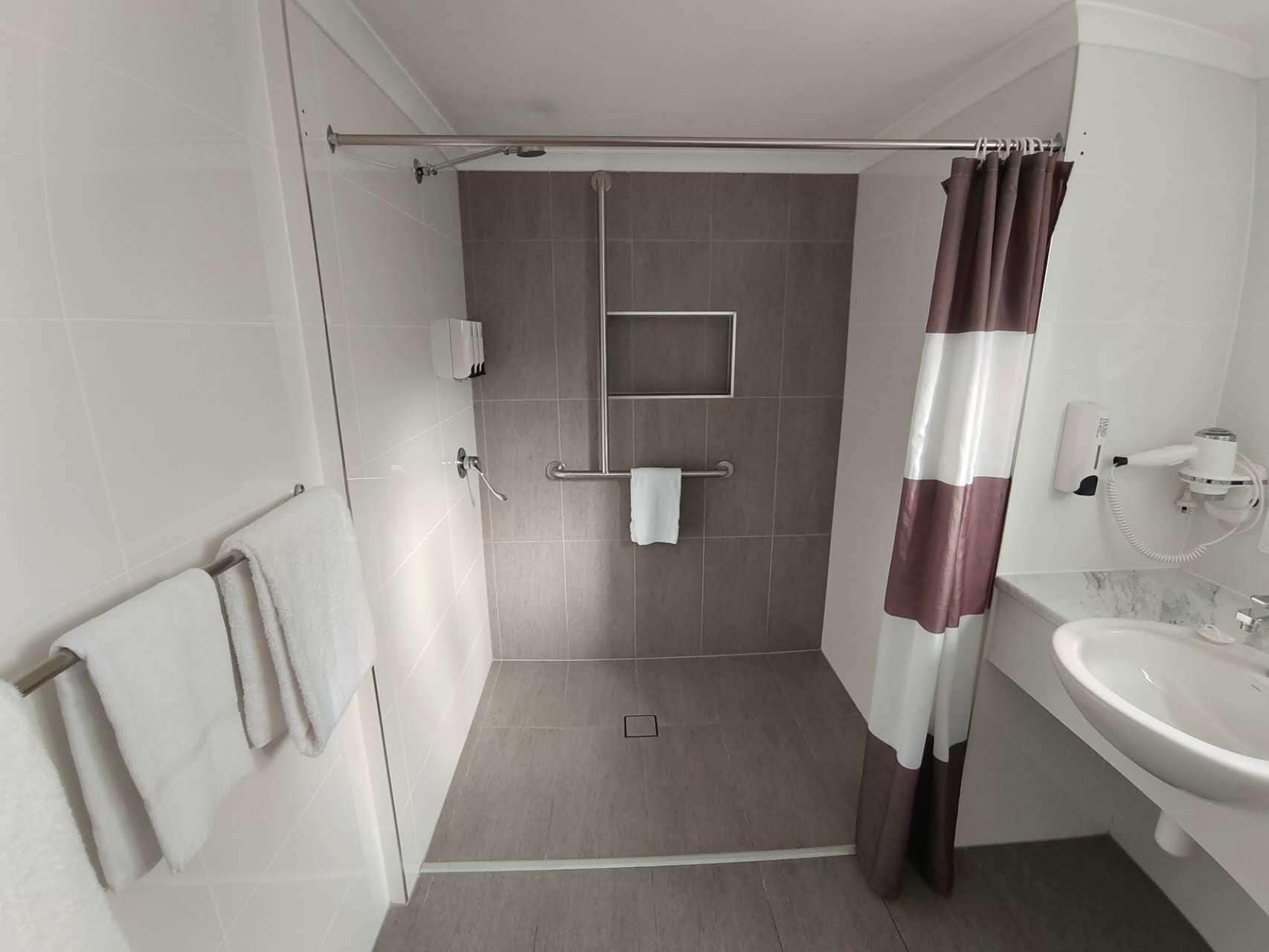 A modern bathroom with a shower, a toilet, and a sink.
