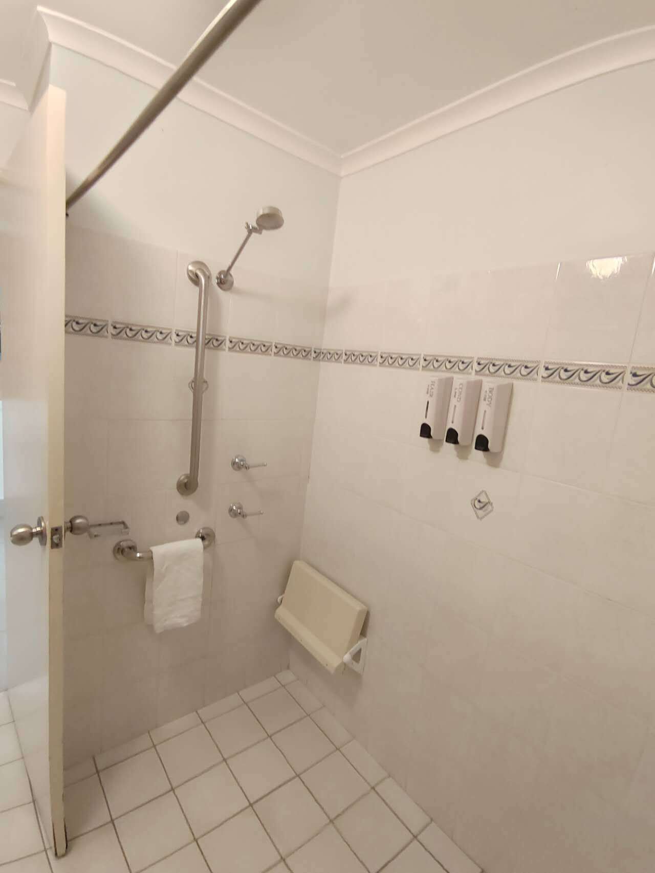 Une salle de bain avec douche, toilettes et porte-serviettes.