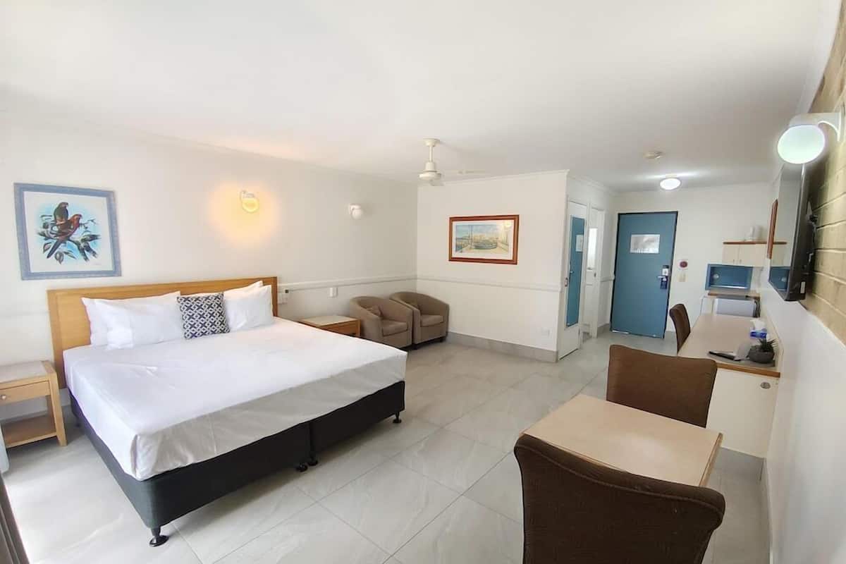 A hotel room with a bed, a desk, a chair, a sofa, and a door.