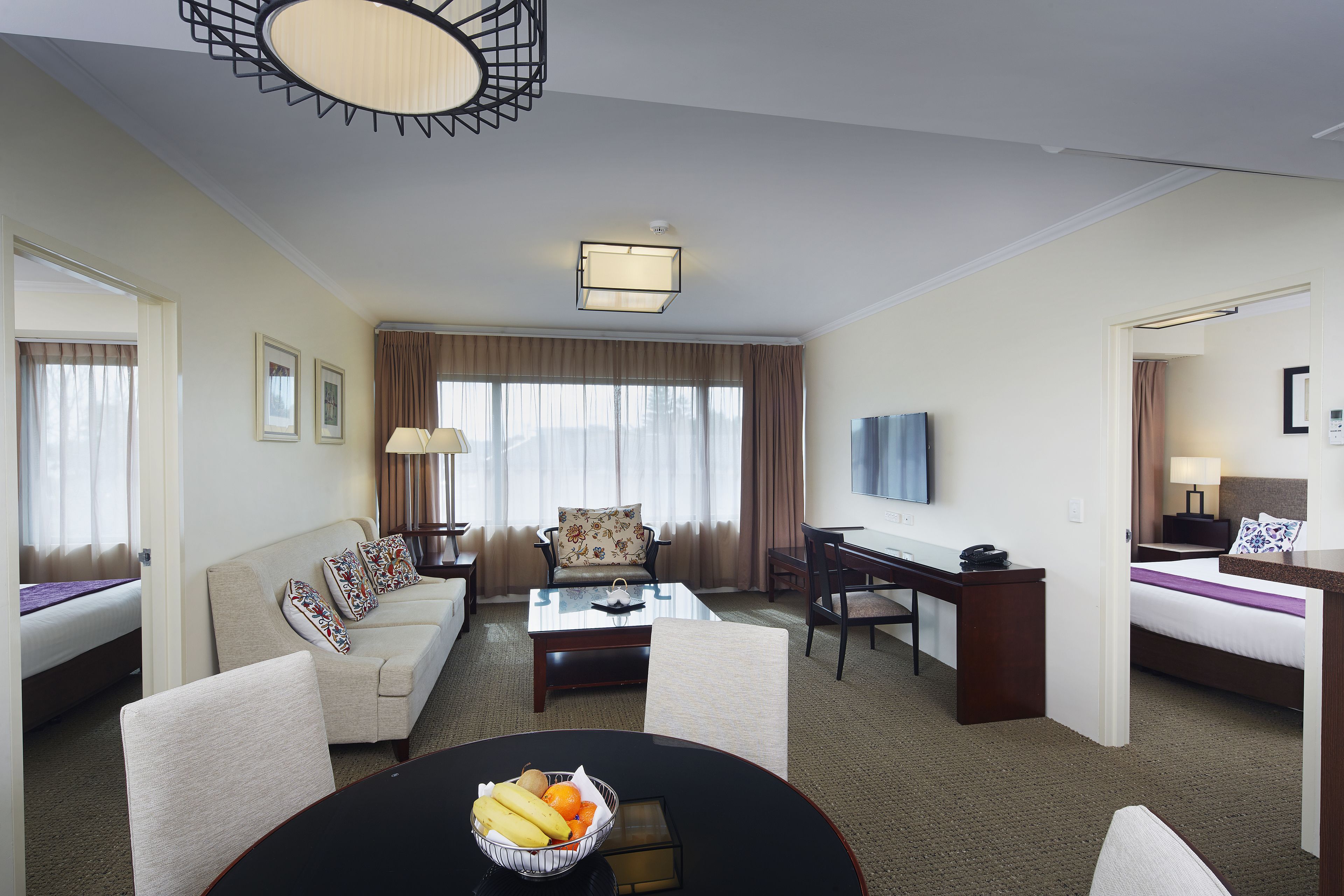 Una habitación de hotel con cama, sofá, escritorio, mesa de centro y televisión.