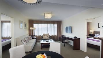 Una habitación de hotel con cama, sofá, escritorio, mesa de centro y televisión.
