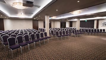 A conference room with rows of purple chairs and a patterned carpet.