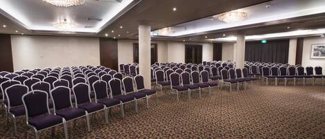 A conference room with rows of purple chairs and a patterned carpet.