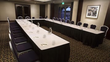 Un salón de conferencias con una larga mesa, sillas y suelo alfombrado.